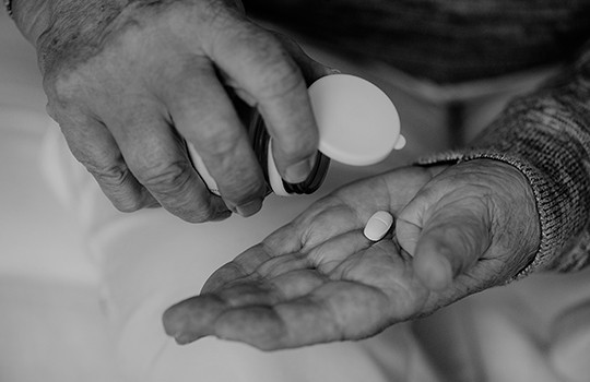 Person taking a pill from a medical bottle