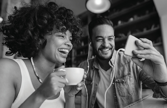 Two people laughing while watching a video on a mobile device